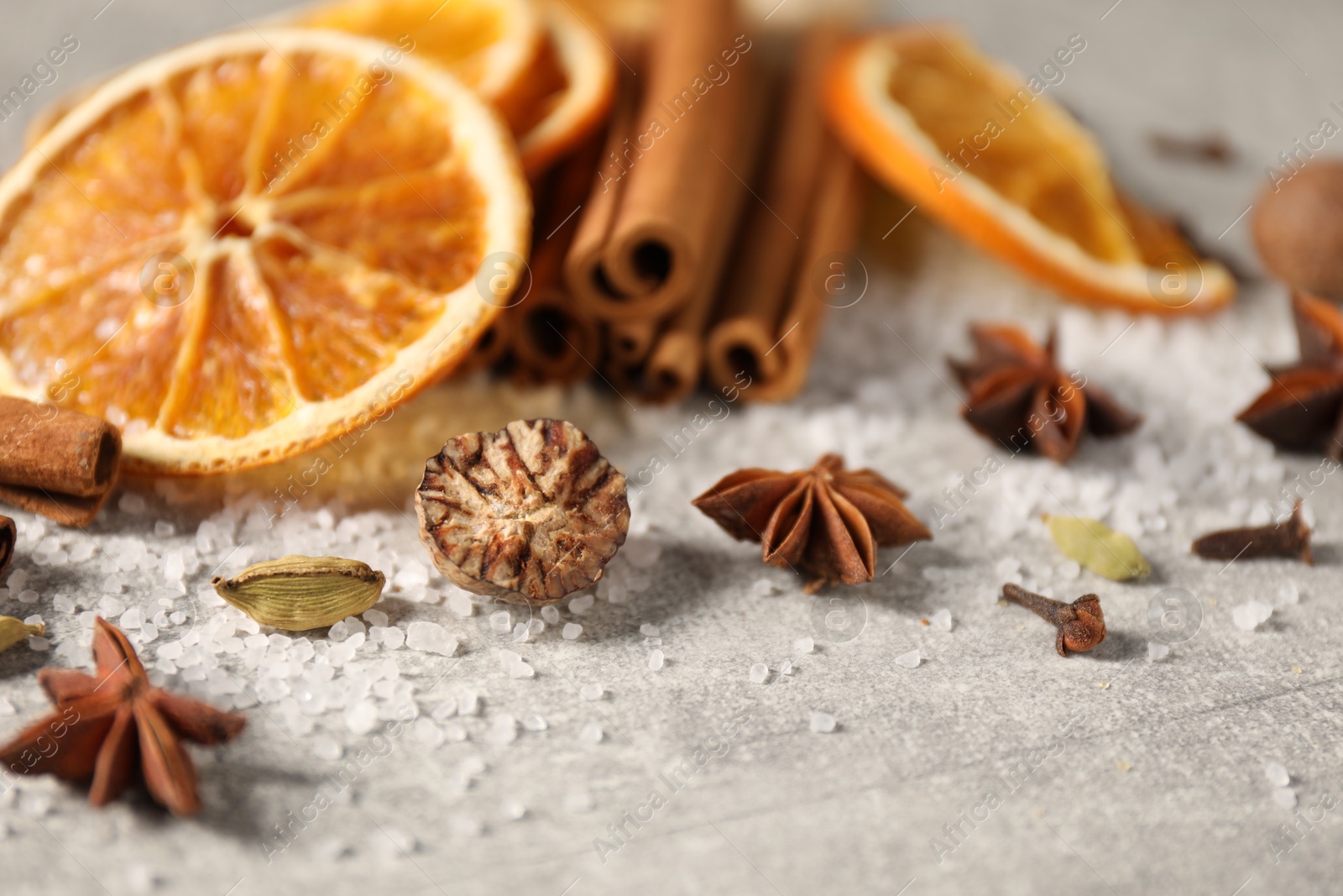 Photo of Different spices and dried orange slices on light grey table, closeup. Christmas season