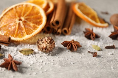 Photo of Different spices and dried orange slices on light grey table, closeup. Christmas season