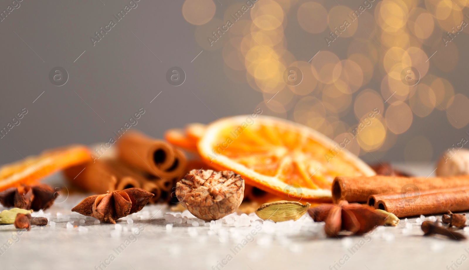 Photo of Different spices and dried orange slices on light grey table, closeup. Christmas season