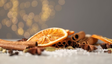 Photo of Different spices and dried orange slices on light grey table, closeup. Christmas season