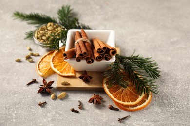 Photo of Different spices, dried orange slices and fir tree branches on light grey table. Christmas season