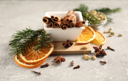 Photo of Different spices, dried orange slices and fir tree branches on light grey table, closeup. Christmas season