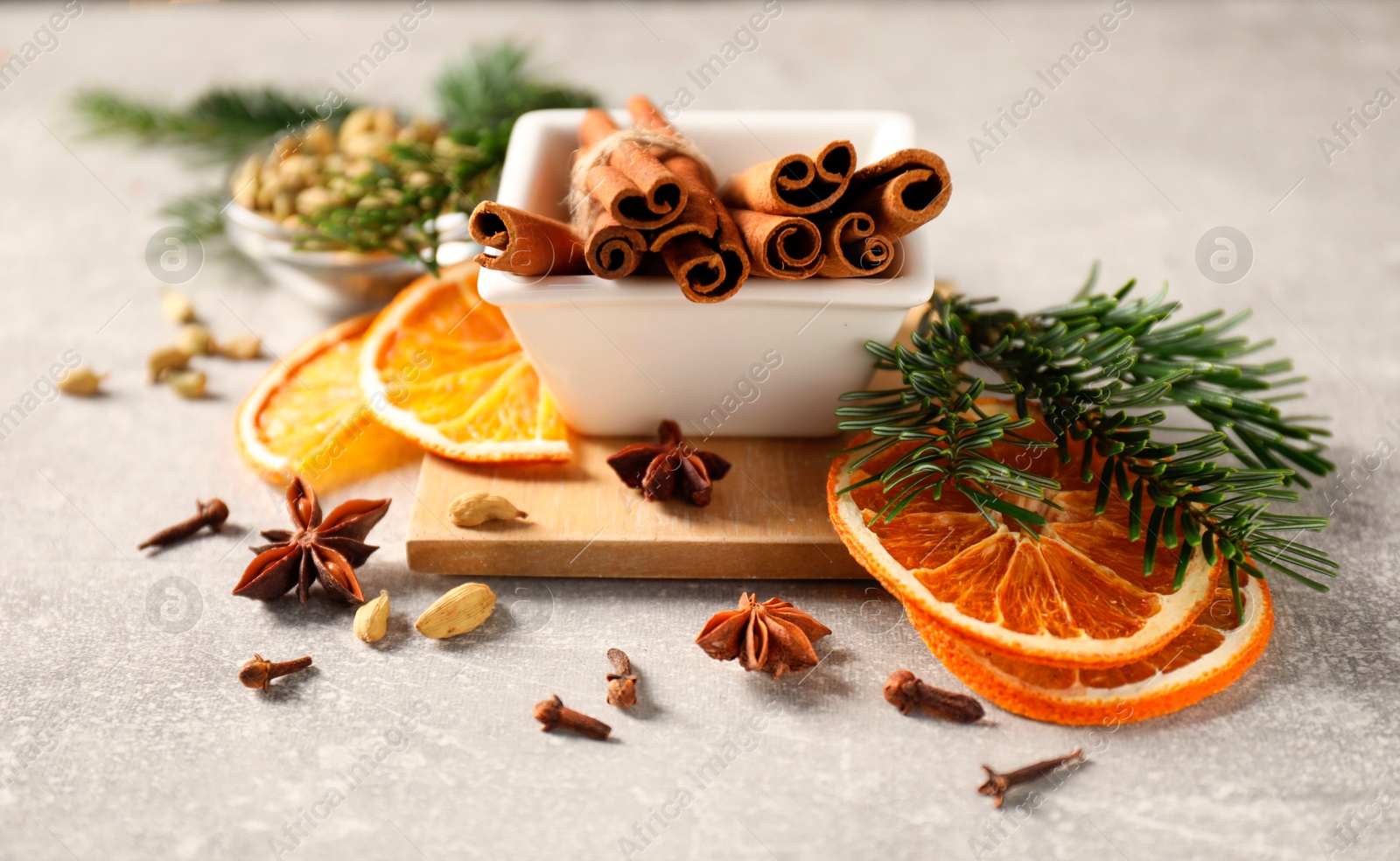 Photo of Different spices, dried orange slices and fir tree branches on light grey table, closeup. Christmas season