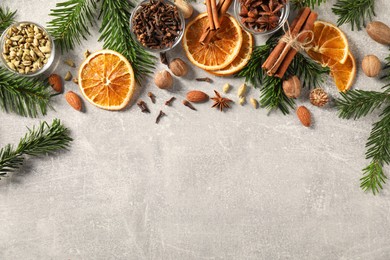 Photo of Different spices, dried orange slices and fir tree branches on light grey table, flat lay with space for text. Christmas season