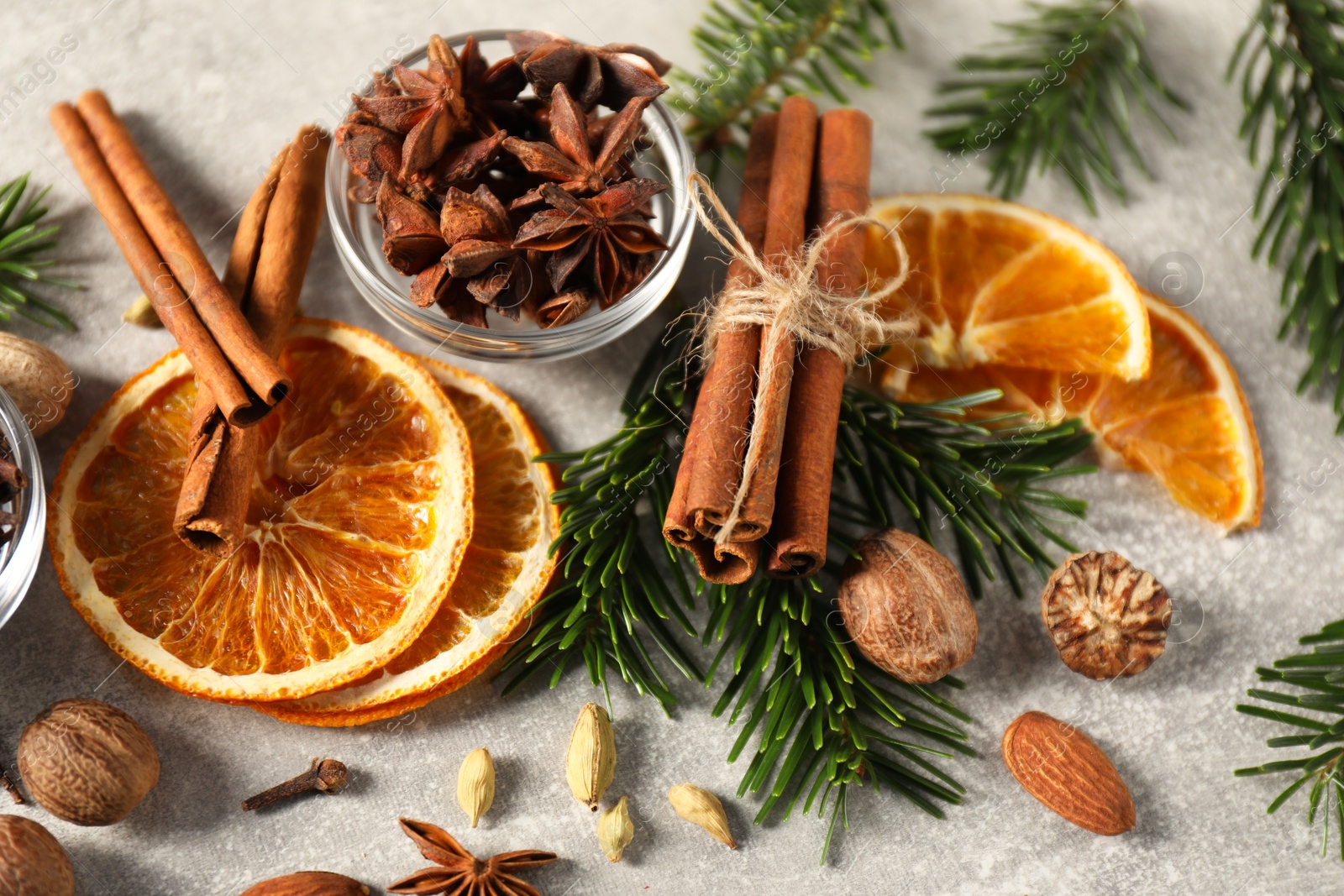 Photo of Different spices, dried orange slices and fir tree branches on light grey table, closeup. Christmas season