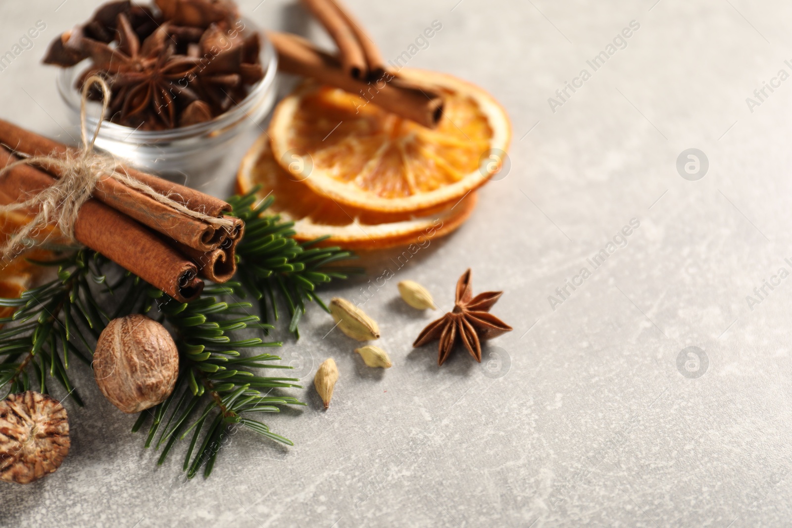 Photo of Different spices, dried orange slices and fir tree branches on light grey table, closeup with space for text. Christmas season