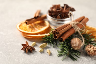 Photo of Different spices, dried orange slices and fir tree branches on light grey table, closeup. Christmas season