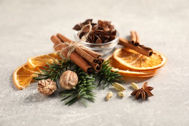 Photo of Different spices, dried orange slices and fir tree branches on light grey table. Christmas season