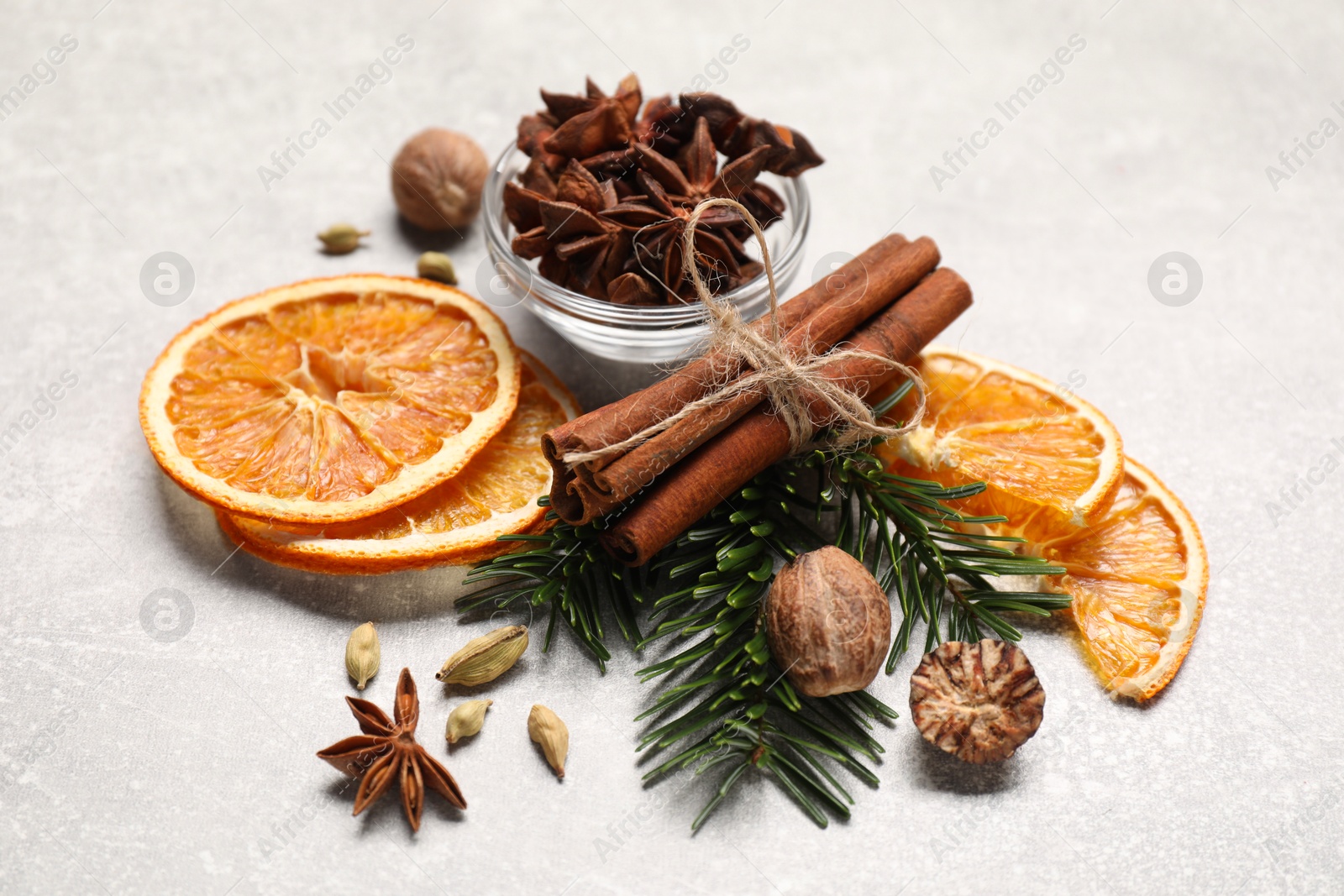 Photo of Different spices, dried orange slices and fir tree branches on light grey table. Christmas season