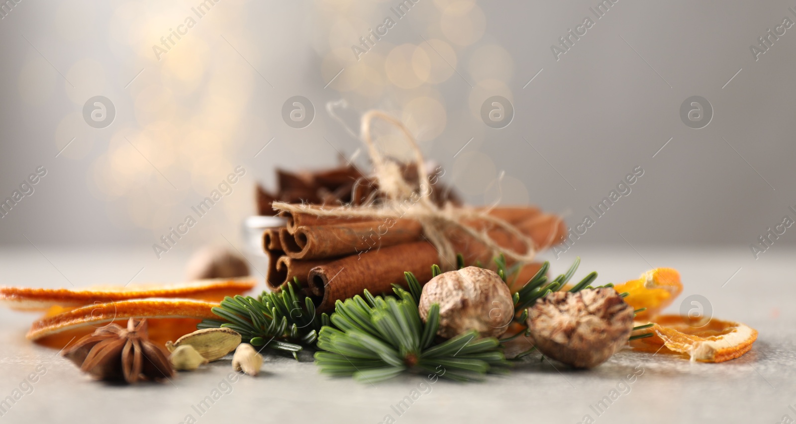 Photo of Different spices, dried orange slices and fir tree branches on light grey table, closeup. Christmas season