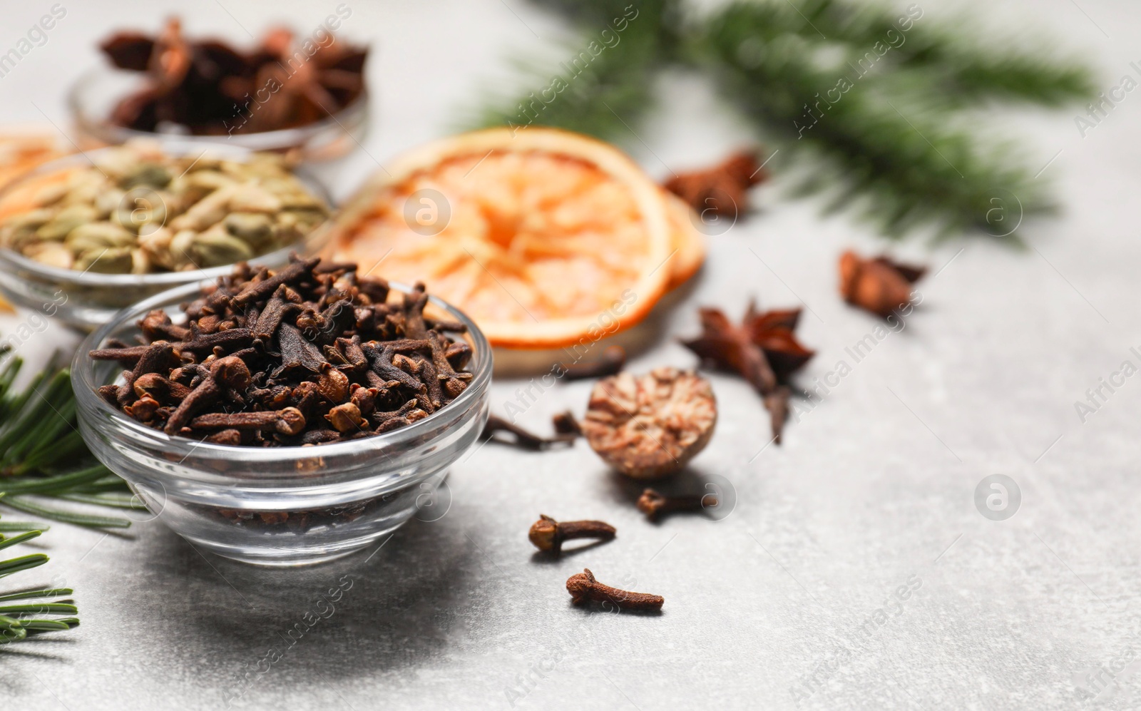 Photo of Different spices, dried orange slices and fir tree branches on light grey table, closeup. Christmas season