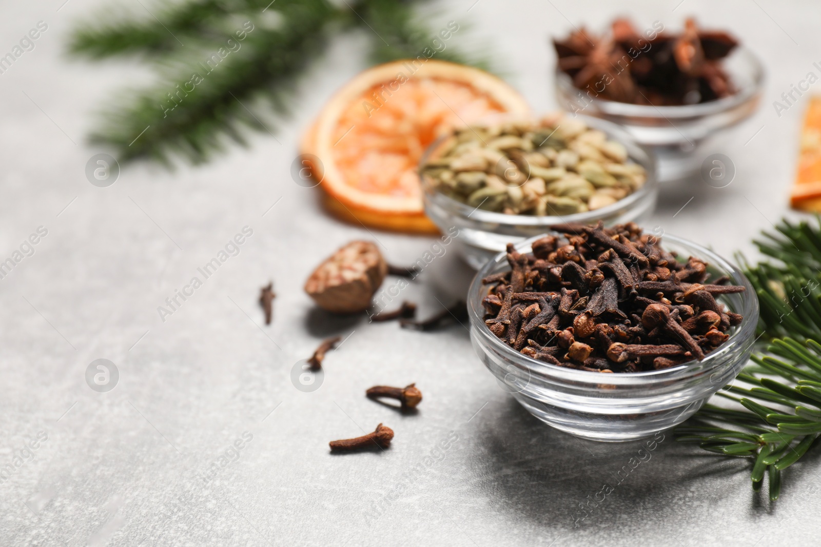 Photo of Different spices, dried orange slices and fir tree branches on light grey table, closeup. Christmas season