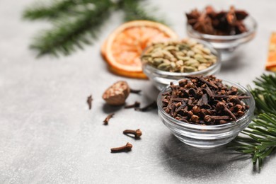 Photo of Different spices, dried orange slices and fir tree branches on light grey table, closeup. Christmas season