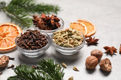 Photo of Different spices, dried orange slices and fir tree branches on light grey table. Christmas season