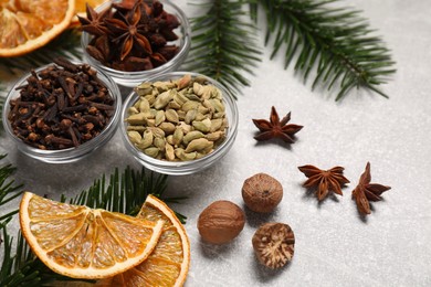 Photo of Different spices, dried orange slices and fir tree branches on light grey table. Christmas season