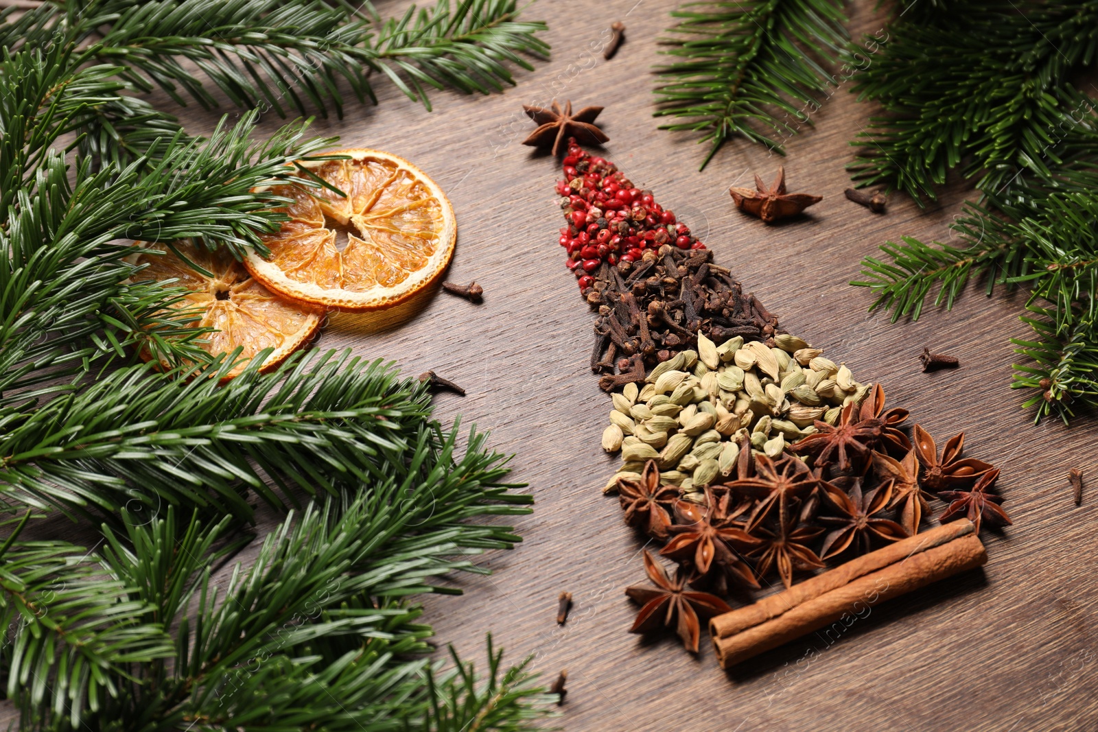 Photo of Christmas tree made of different spices, dried orange slices and fir branches on wooden table