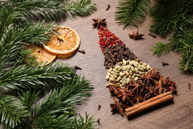 Photo of Christmas tree made of different spices, dried orange slices and fir branches on wooden table