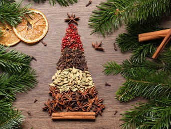 Photo of Christmas tree made of different spices, dried orange slices and fir branches on wooden table, flat lay