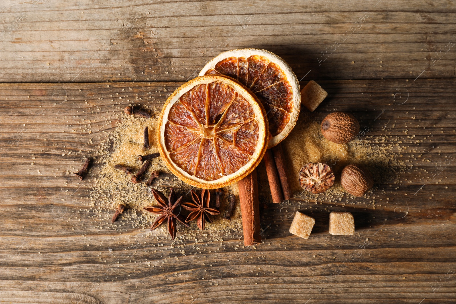 Photo of Different spices and dried orange slices on wooden table, flat lay. Christmas season