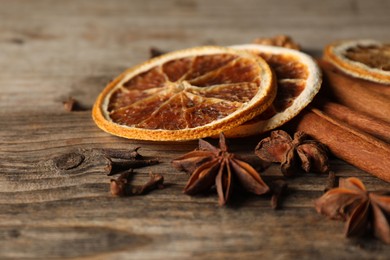 Photo of Different spices and dried orange slices on wooden table, closeup. Christmas season