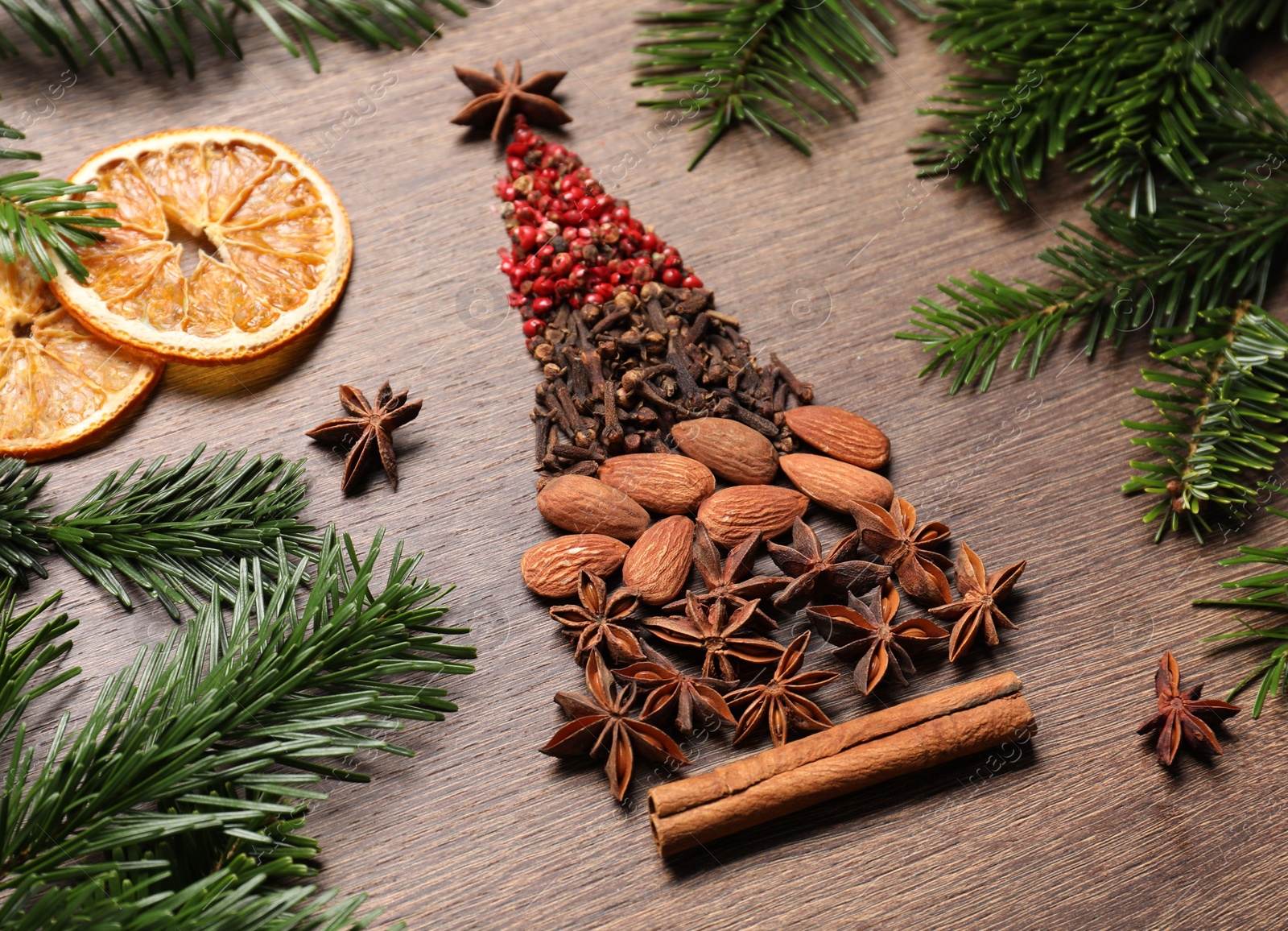 Photo of Christmas tree made of different spices, dried orange slices and fir branches on wooden table