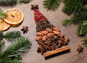 Photo of Christmas tree made of different spices, dried orange slices and fir branches on wooden table