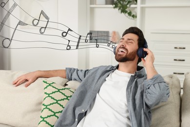 Image of Happy man with headphones singing on sofa indoors. Music notes flying out of his mouth