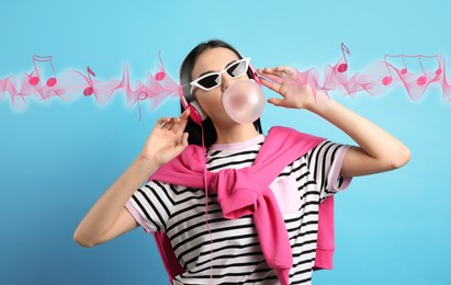 Image of Fashionable young woman with headphones blowing bubblegum on light blue background. Music notes and sound waves flying near her