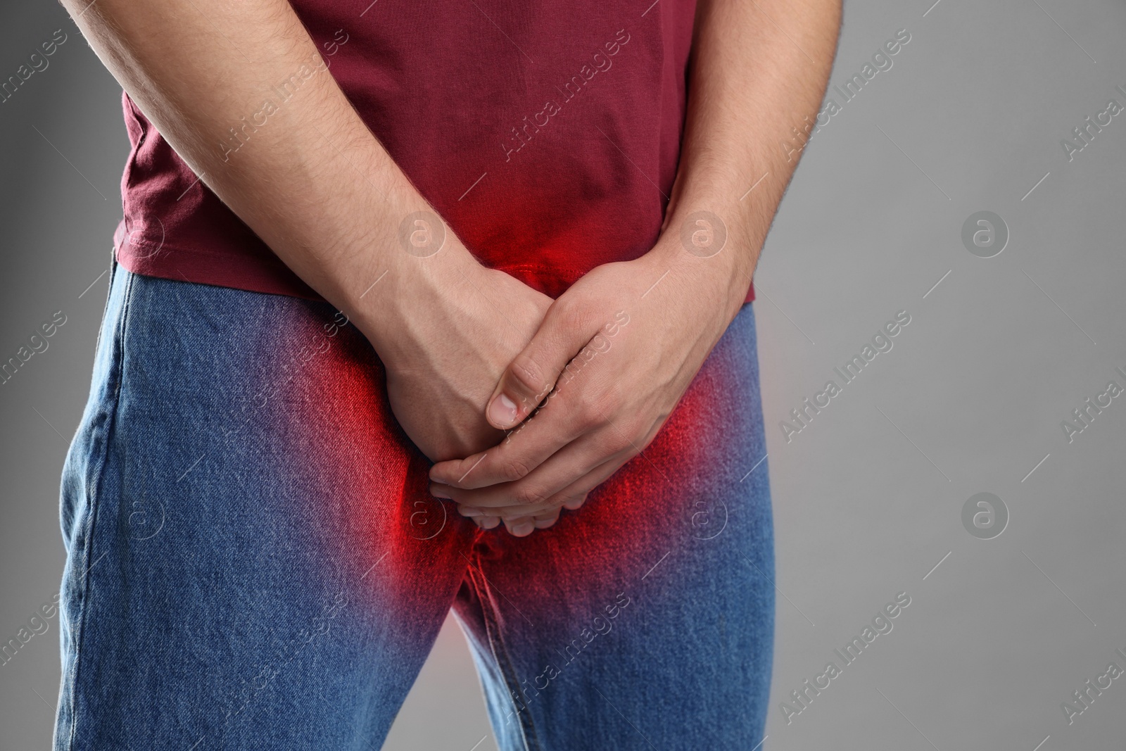 Image of STD (sexually transmitted diseases). Man holding hands near his groin on grey background, closeup. Space for text