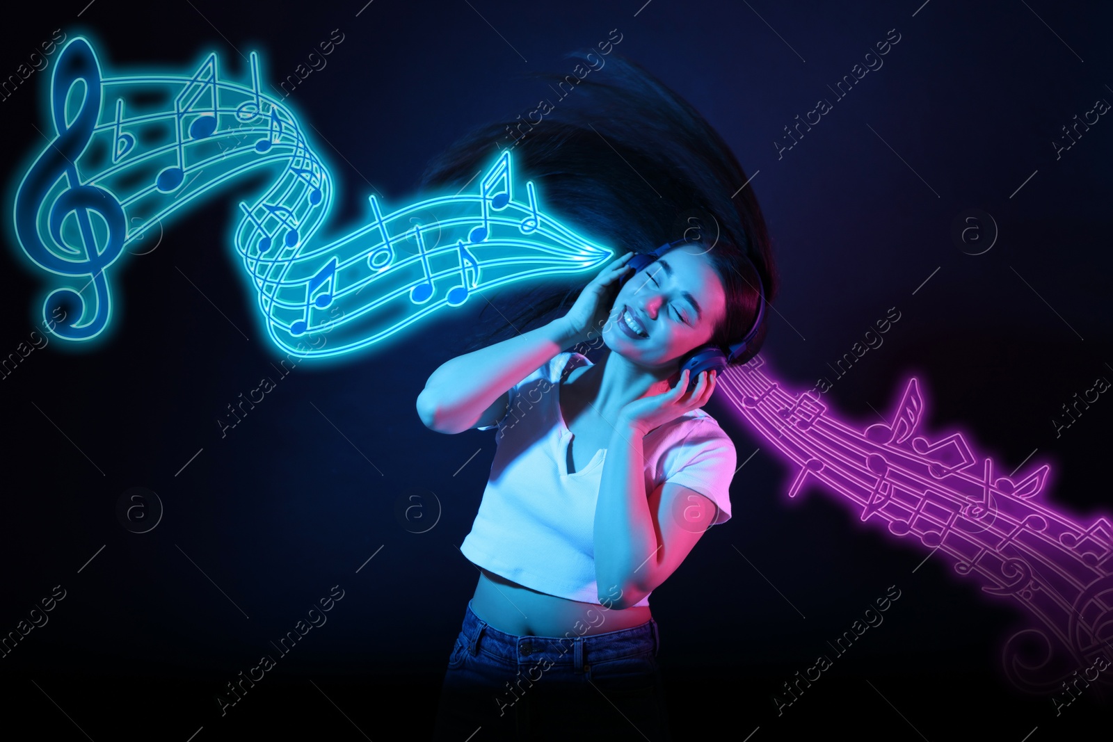 Image of Happy woman with headphones dancing in neon lights against dark blue background. Music notes flying near her