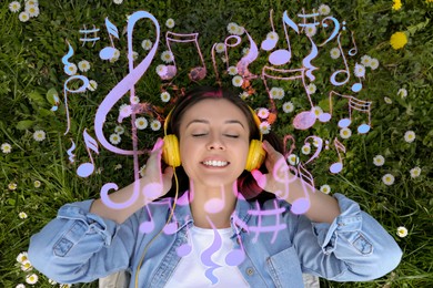 Image of Happy woman with headphones lying on green grass, top view. Heart of music notes around near her