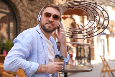 Image of Happy young man with coffee and headphones at outdoor cafe. Music notes flying near him