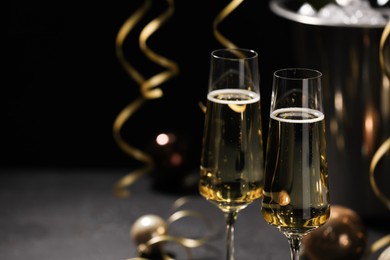 Photo of Champagne in glasses and Christmas decor on grey table, space for text