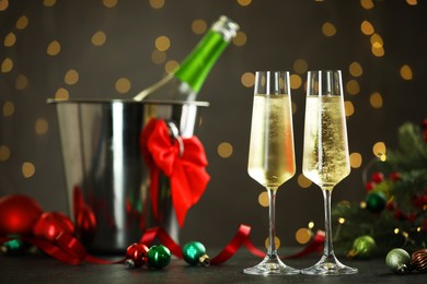 Photo of Delicious champagne in glasses and Christmas decor on grey table against blurred lights, space for text