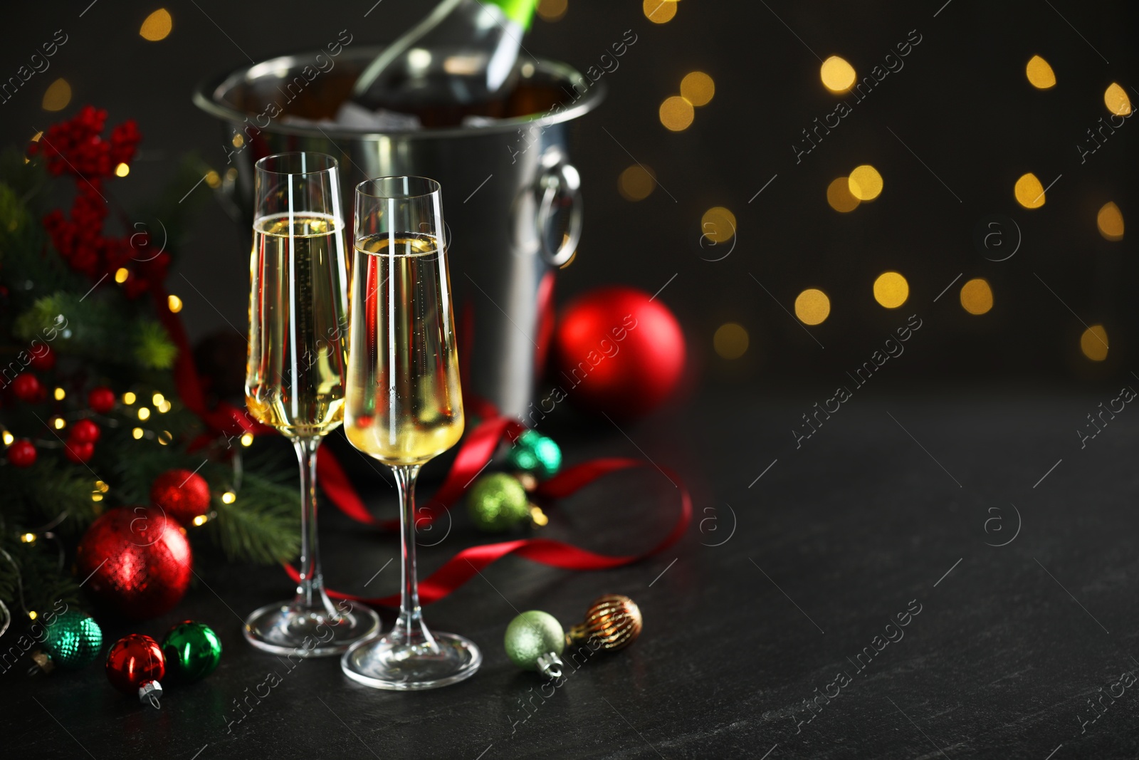 Photo of Delicious champagne in glasses and Christmas decor on grey table against blurred lights, space for text