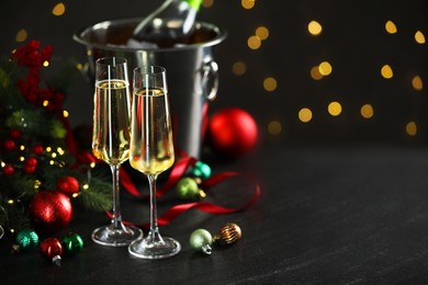 Photo of Delicious champagne in glasses and Christmas decor on grey table against blurred lights, space for text