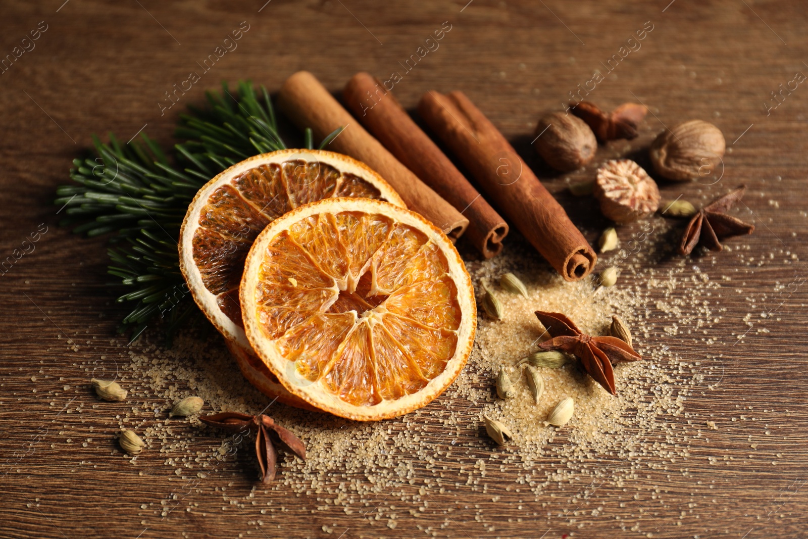 Photo of Different spices, dried orange slices and fir tree branches on wooden table. Christmas season