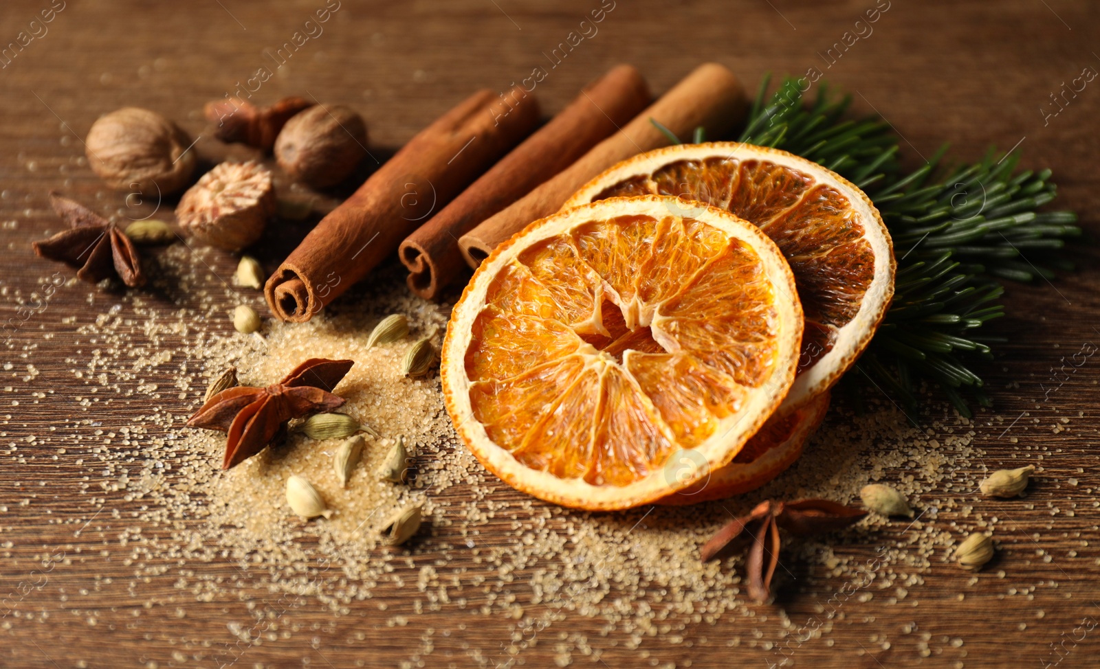 Photo of Different spices, dried orange slices and fir tree branches on wooden table, closeup. Christmas season