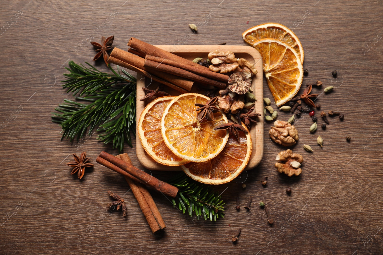 Photo of Different spices, dried orange slices and fir tree branches on wooden table, flat lay. Christmas season