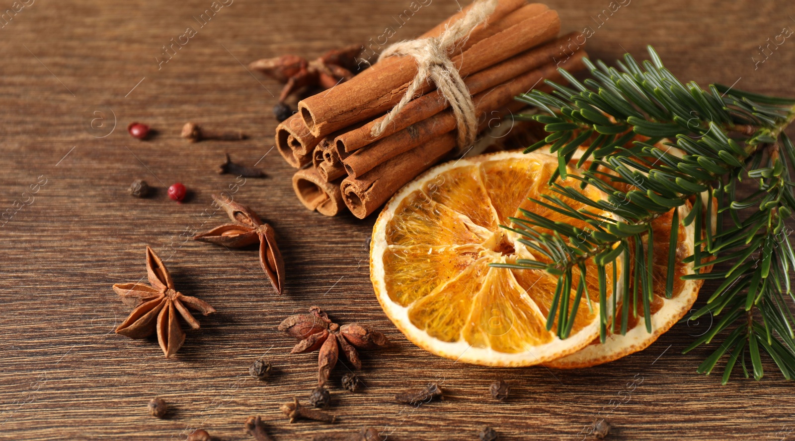 Photo of Different spices, dried orange slices and fir tree branches on wooden table, closeup. Christmas season