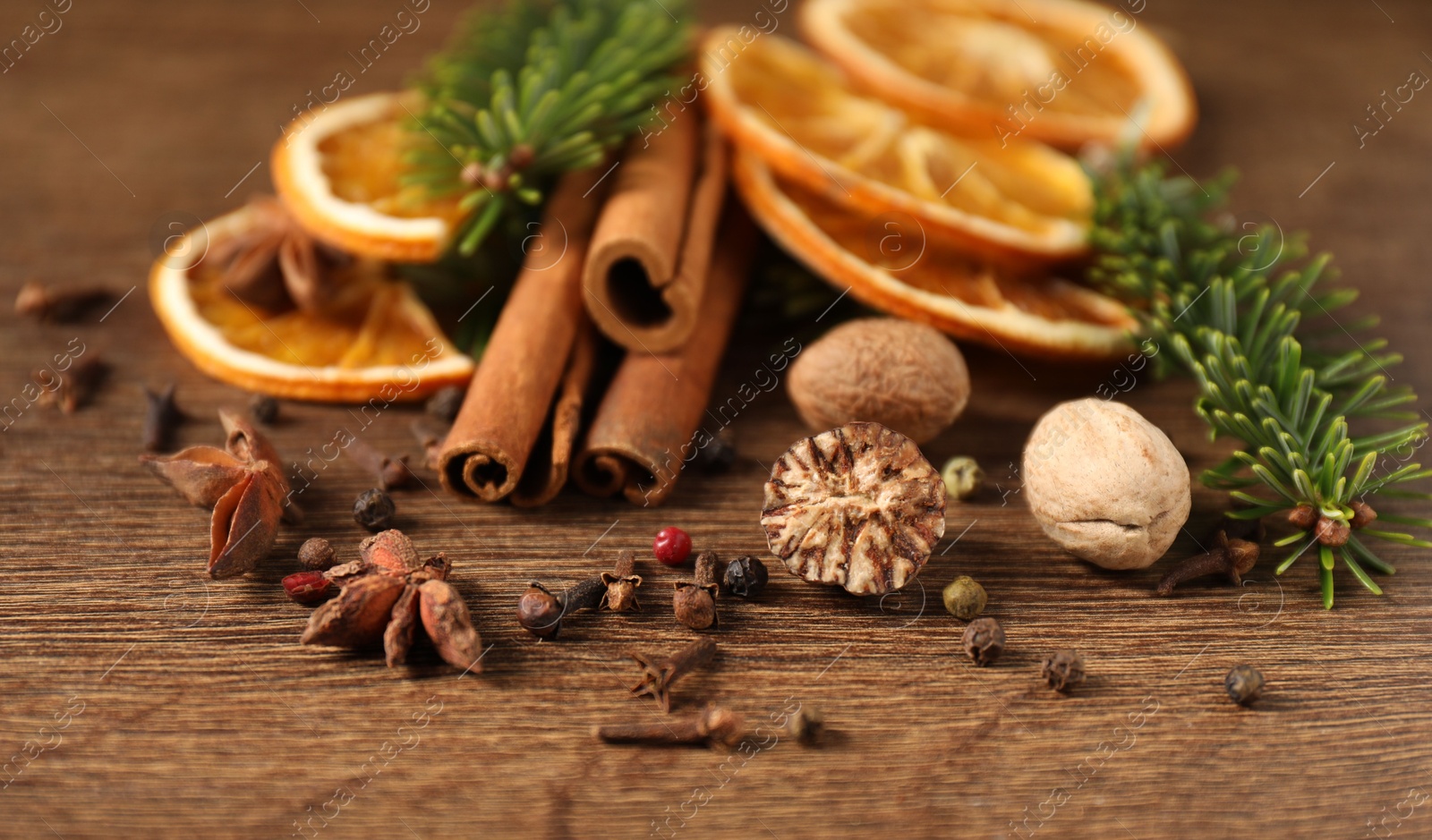 Photo of Different spices, dried orange slices and fir tree branches on wooden table, closeup. Christmas season