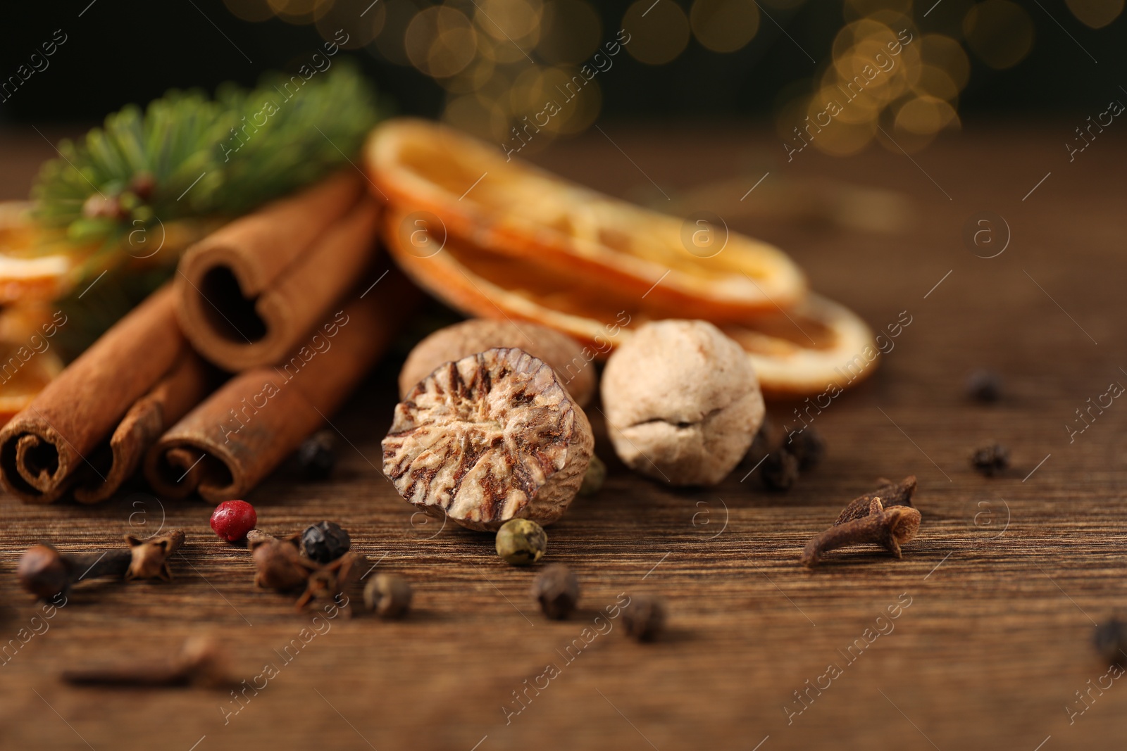 Photo of Different spices, dried orange slices and fir tree branches on wooden table, closeup. Christmas season