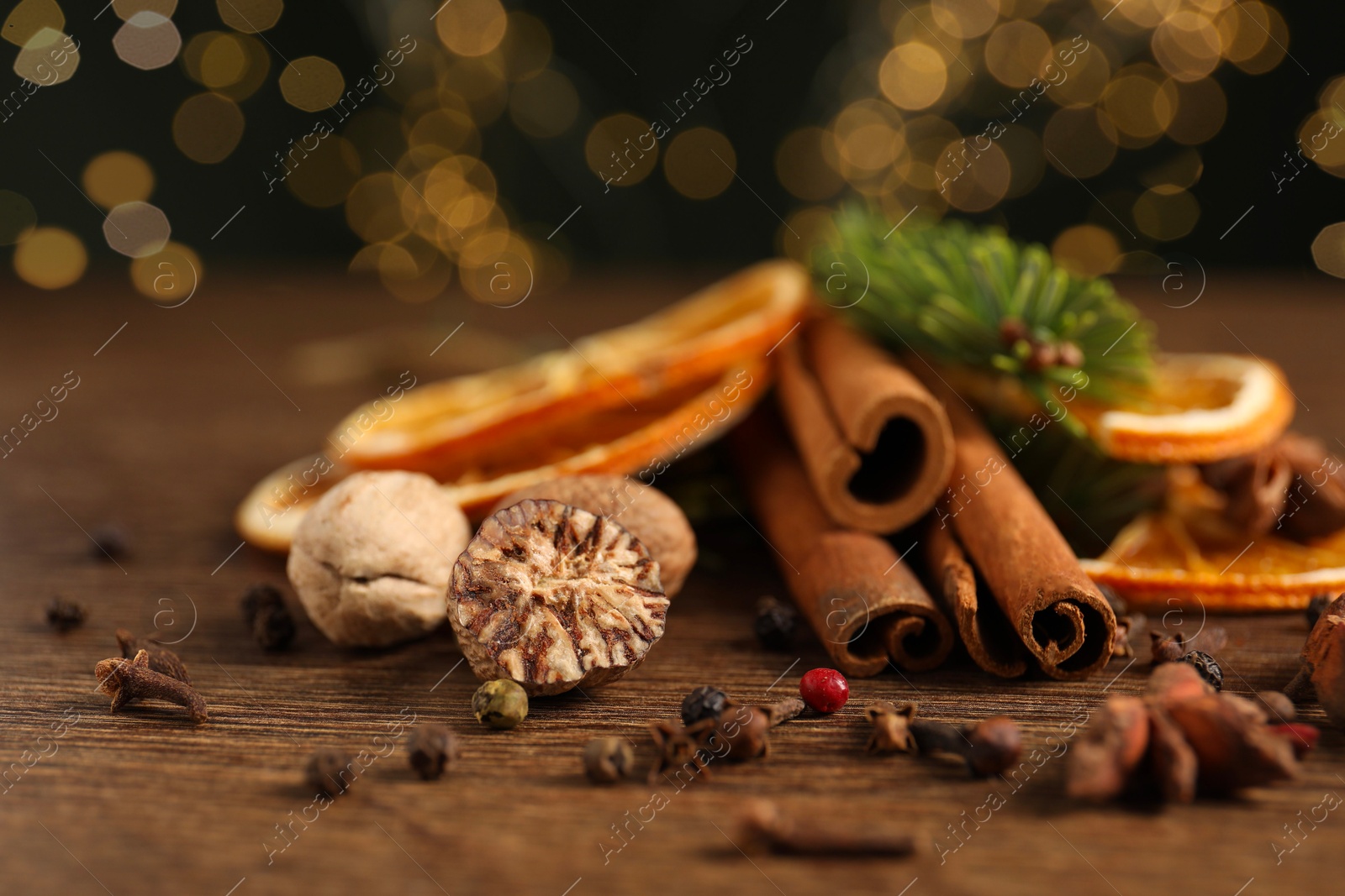 Photo of Different spices, dried orange slices and fir tree branches on wooden table, closeup. Christmas season