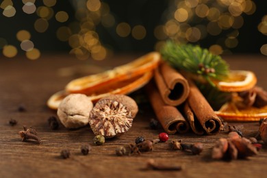 Photo of Different spices, dried orange slices and fir tree branches on wooden table, closeup. Christmas season