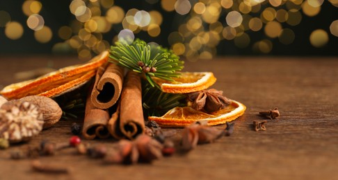 Photo of Different spices, dried orange slices and fir tree branches on wooden table, closeup with space for text. Christmas season