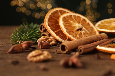 Photo of Different spices, dried orange slices and fir tree branches on wooden table, closeup. Christmas season