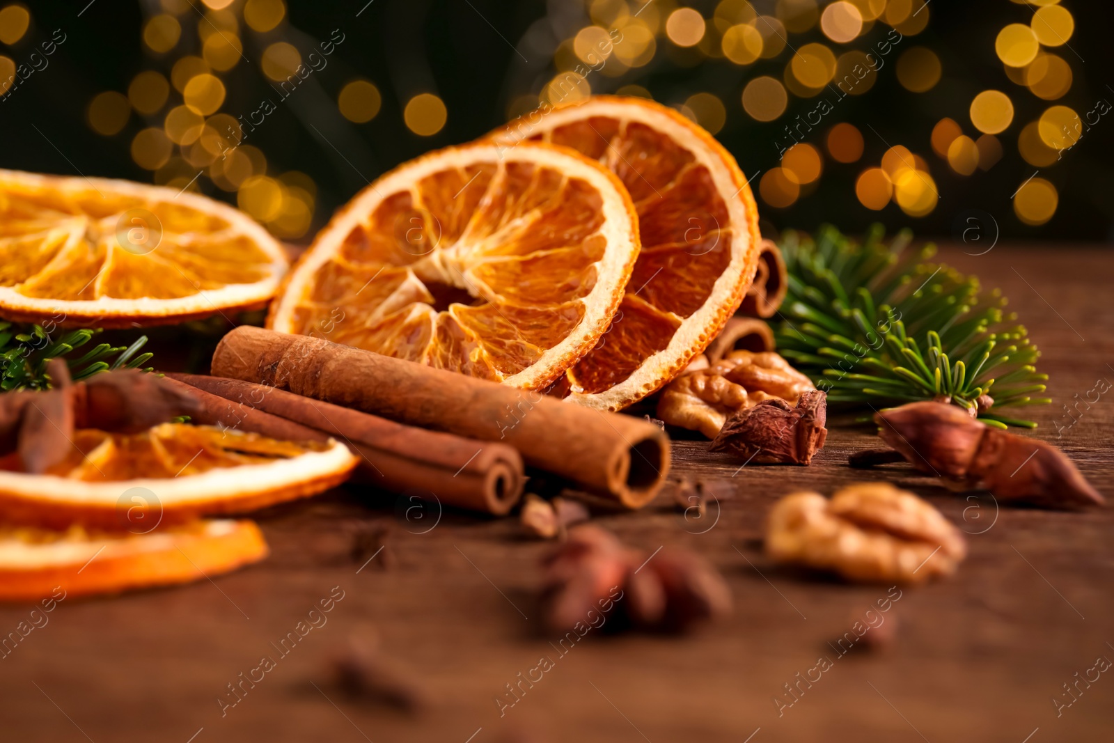 Photo of Different spices, dried orange slices and fir tree branches on wooden table, closeup. Christmas season