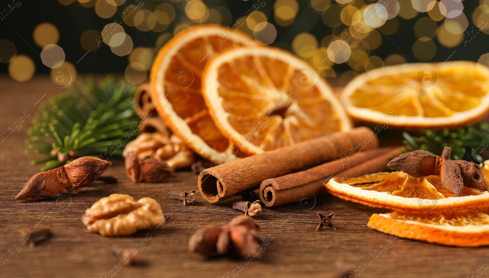 Photo of Different spices, dried orange slices and fir tree branches on wooden table, closeup. Christmas season