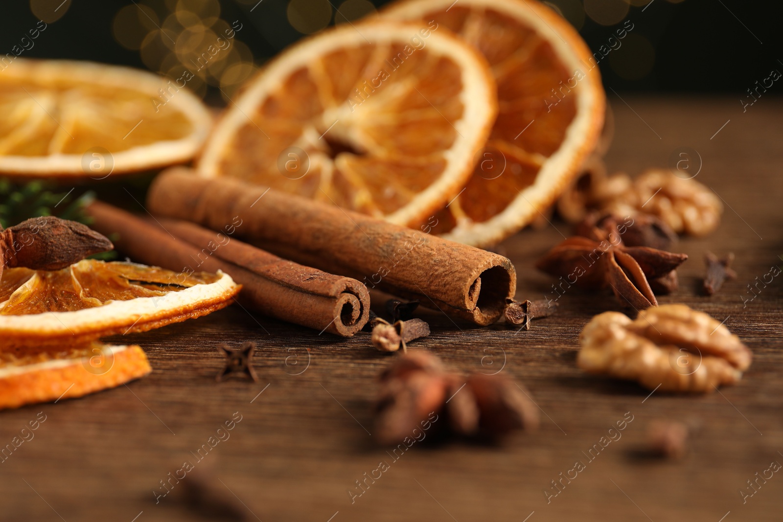 Photo of Different spices and dried orange slices on wooden table, closeup. Christmas season