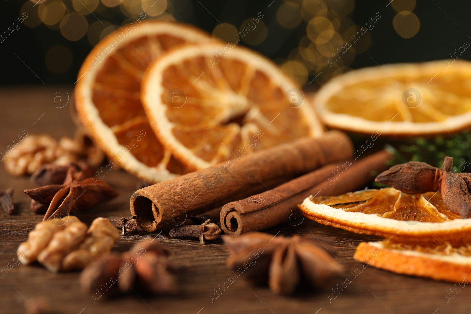 Photo of Different spices and dried orange slices on wooden table, closeup. Christmas season